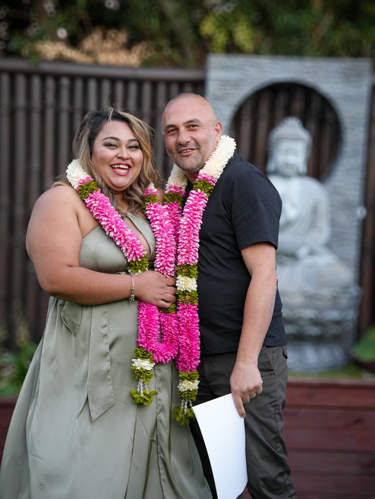 Newlyweds laughing in traditional flower garlands at their multicultural wedding in Sydney