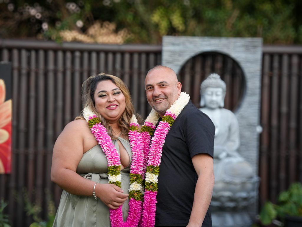 Fijian wedding in Sydney — a couple wearing pink and white flower garlands at their backyard ceremony