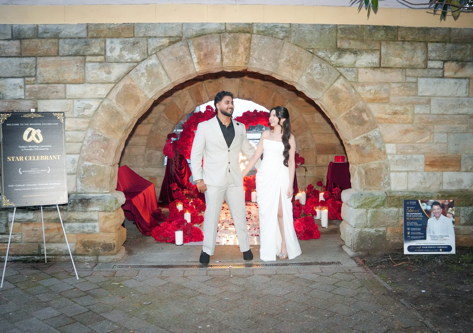 Candlelit wedding ceremony under a sandstone arch at Milsons Point styled with red roses, officiated by Star Celebrant